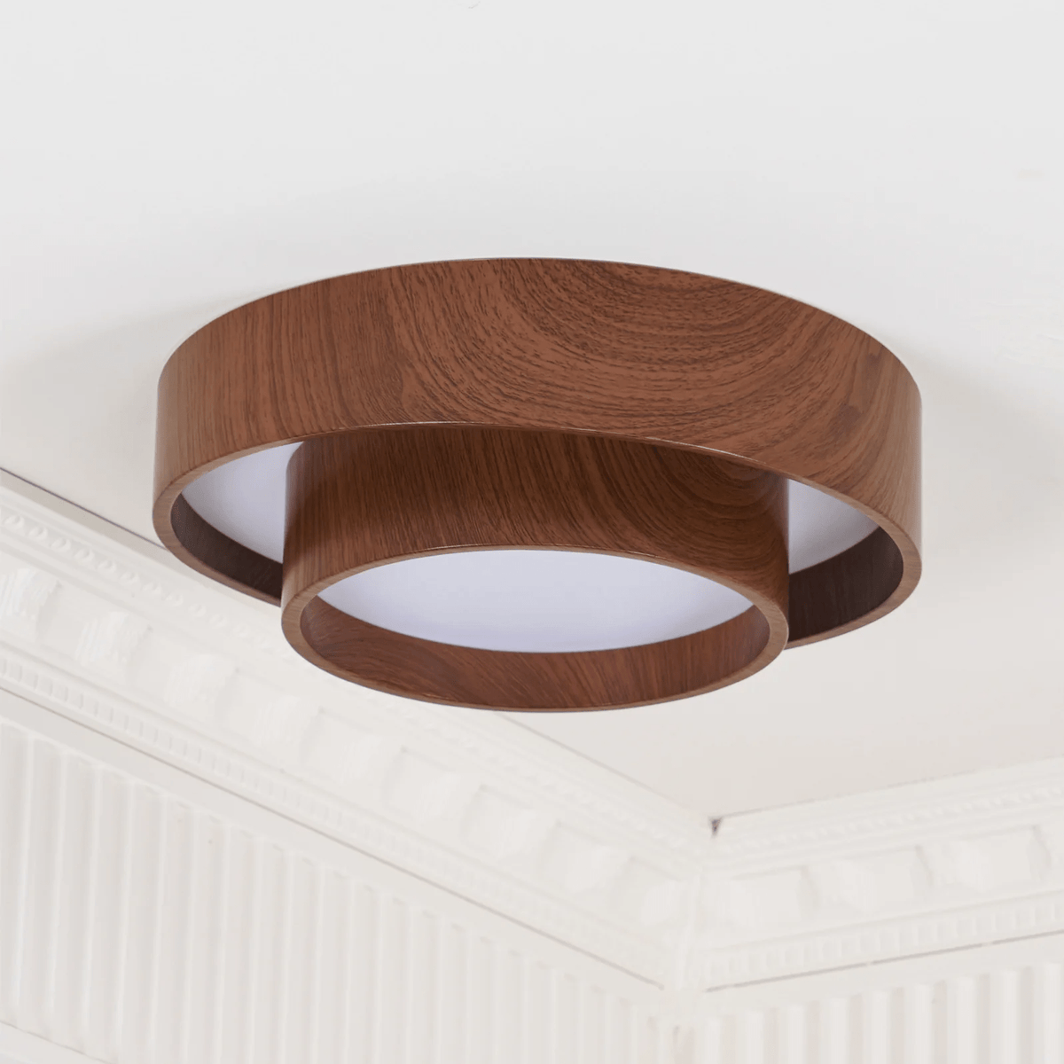 Clérachic wood-grain ceiling light seen from below at an angle, with a white diffuser and ornate white cornice behind.