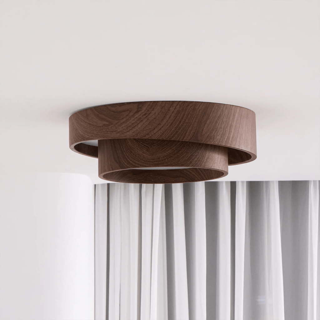 Side view of a Clérachic ceiling light with two stepped wood-grain rings, hung over white curtains on a pale wall.