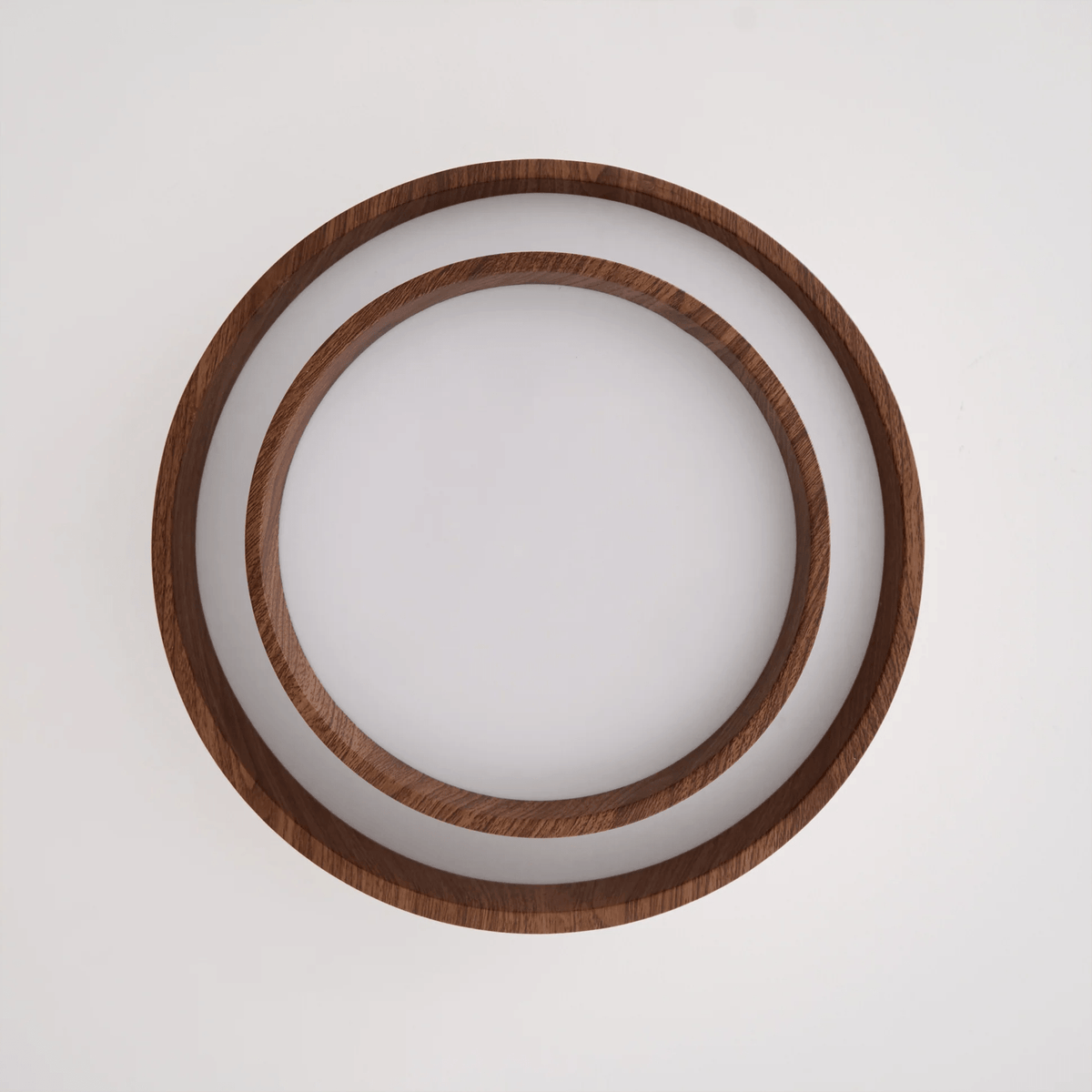Clérachic ceiling light seen from directly below, unlit, showing two concentric wood-grain rings around a white diffuser.