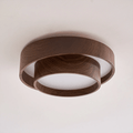 Clérachic ceiling light seen from a low angle on a pale ceiling, with a thick walnut-look ring and a smaller ring below it.