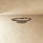Clérachic two-ring LED chandelier with irregular wavy rings in dark bronze metal, glowing softly on fine suspension cables.
