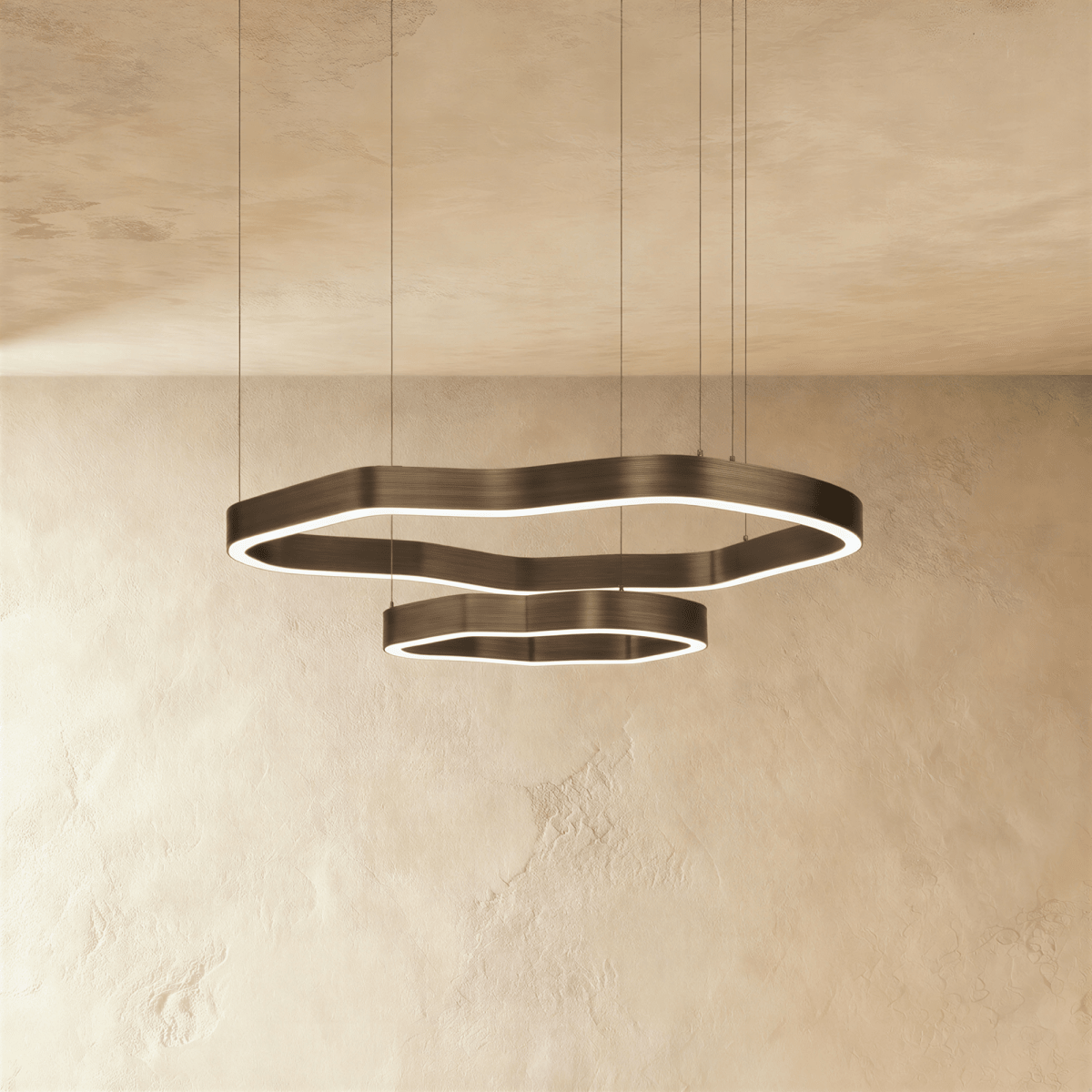 Clérachic large two-ring LED chandelier, wavy bronze-toned rings with a lit inner edge, hanging below a textured plaster ceiling.