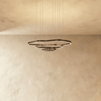 Clérachic three-ring LED chandelier with layered wavy rings in dark bronze metal and a soft glowing edge, on a limewash wall.