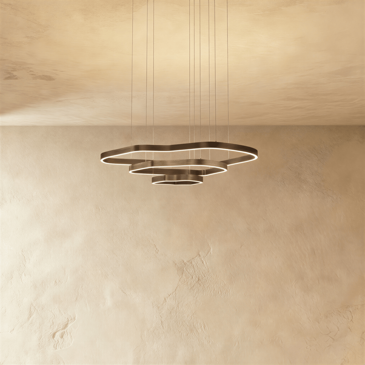 Clérachic three-ring LED chandelier with layered wavy rings in dark bronze metal and a soft glowing edge, on a limewash wall.