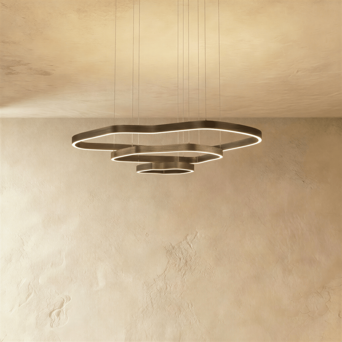 Clérachic wider three-ring LED chandelier, stepped wavy bronze rings with built-in light, hung on cables against plaster.