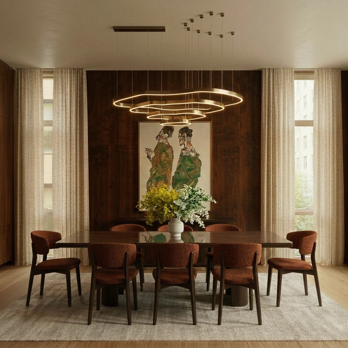 Clérachic four-ring brass LED chandelier hung over a long walnut dining table with rust-coloured chairs and a vase of flowers.