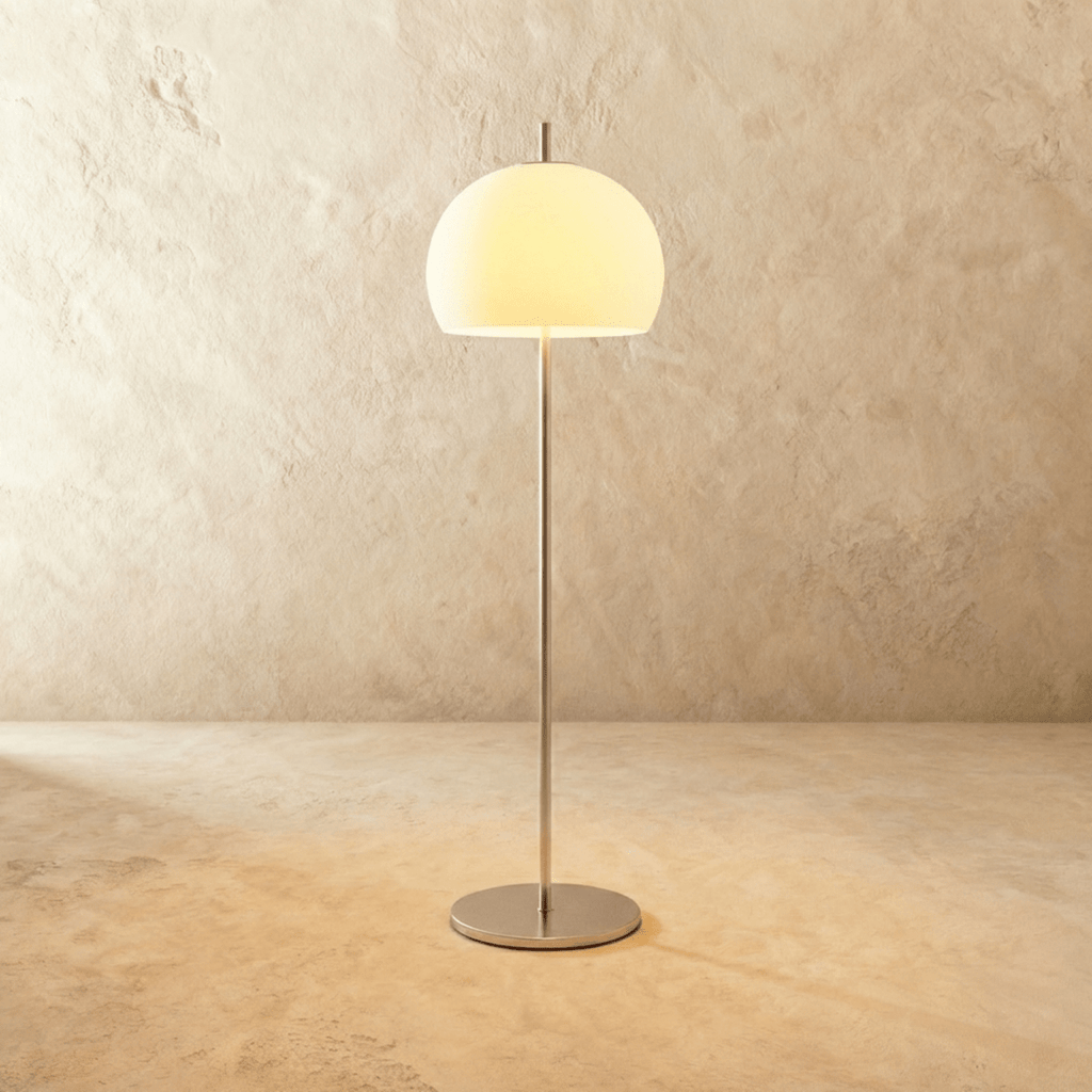 Clérachic floor lamp with a milky white glass dome glowing warm on a slim chrome stem and a flat round base.