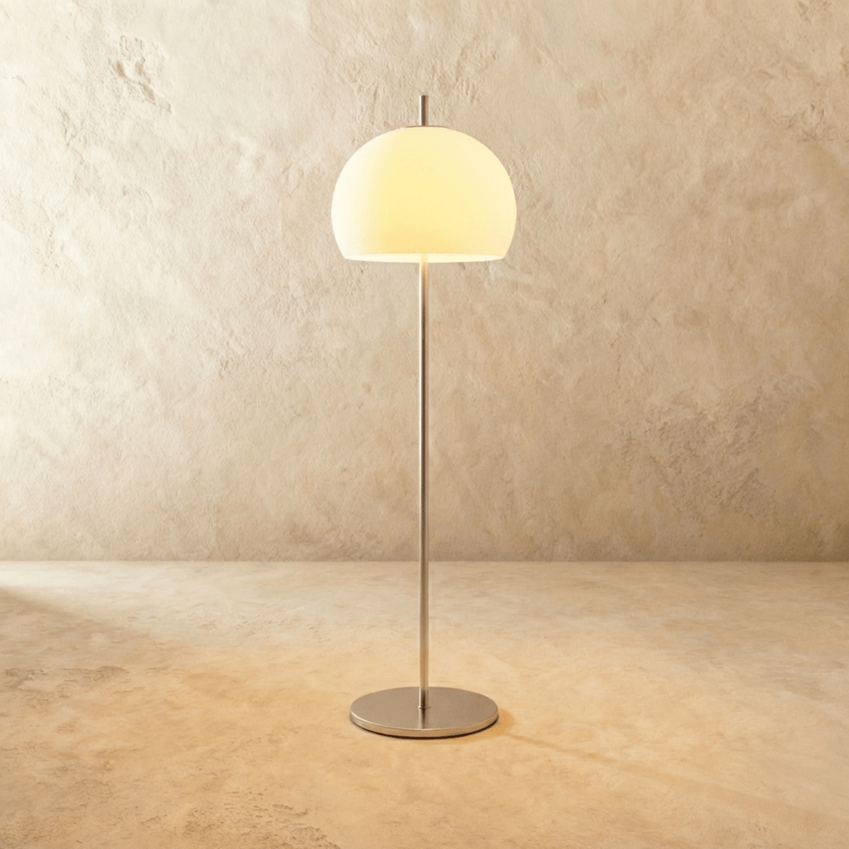 Clérachic floor lamp with a milky white glass dome glowing warm on a slim chrome stem and a flat round base.