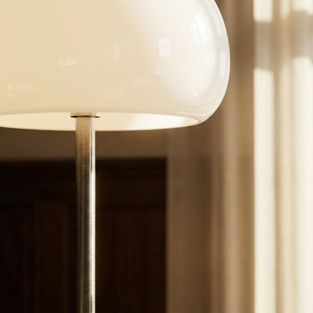 Clérachic floor lamp detail showing the underside of a cream glass dome and the brushed chrome stem below it.