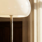 Clérachic floor lamp detail showing the underside of a cream glass dome and the brushed chrome stem below it.
