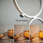 Clérachic white ring floor lamp, close up of its touch switch above three room shots of the lamp at different light levels.
