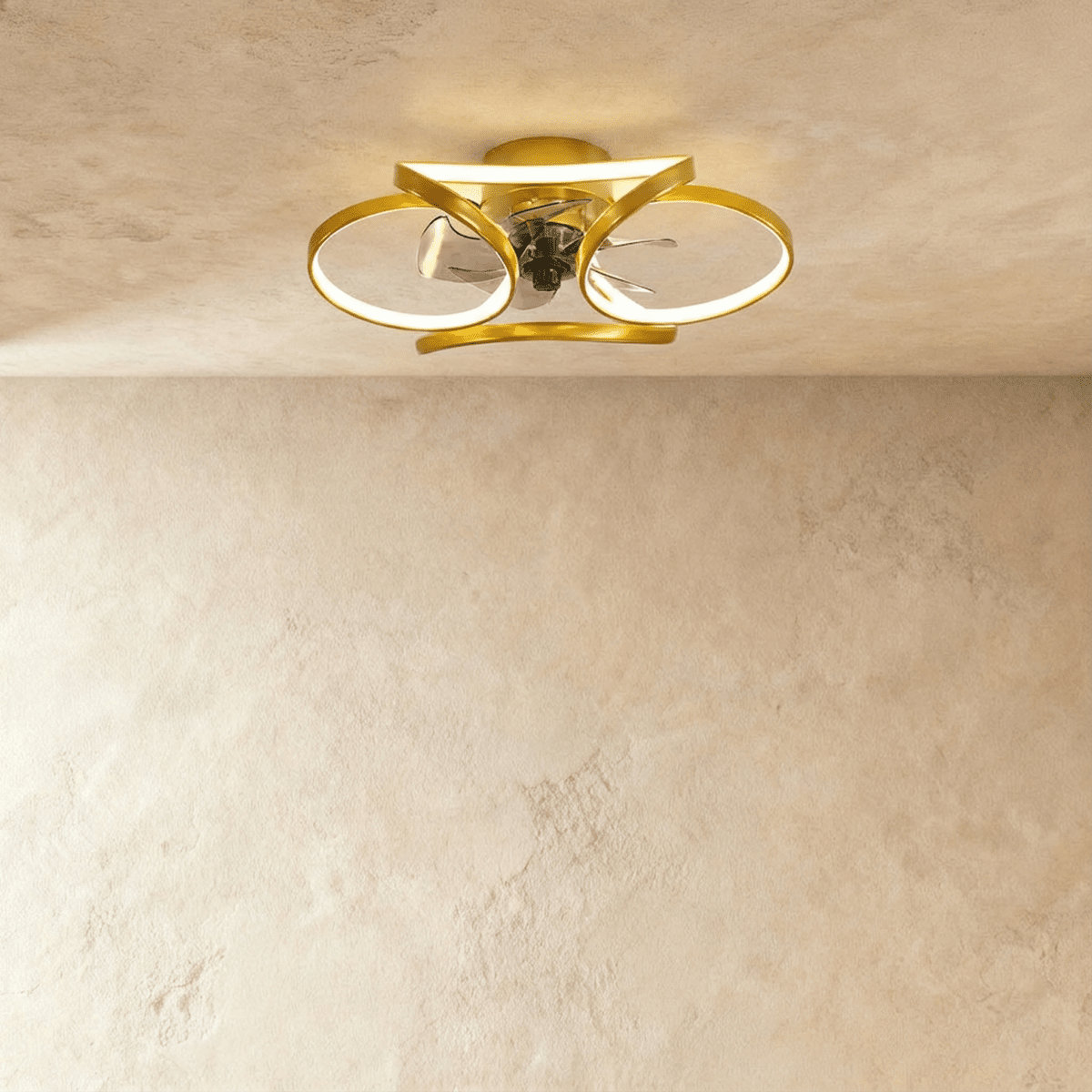 Clérachic ceiling fan with a light in gold, looped LED bands glowing warm around a small central fan in a studio.