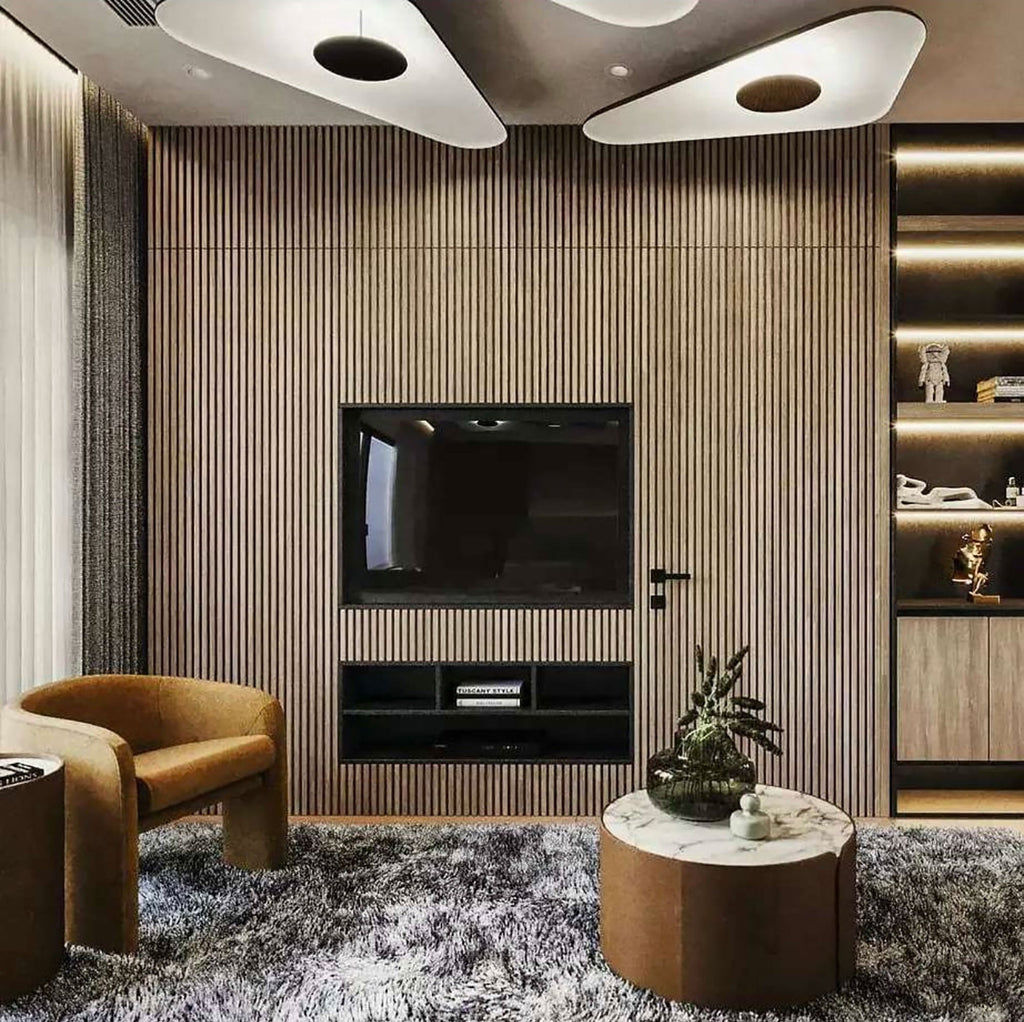Two white triangular-edged disc pendants glow above a timber-slat wall with a television and a tan armchair, shown with this Clérachic pendant.