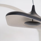 Close view of the black rim of this Clérachic disc pendant and its pale inner surface, with the dark centre plate in focus.