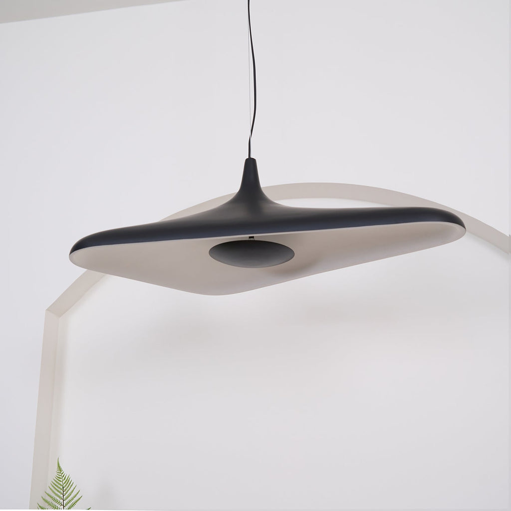 The underside of a black disc pendant shows a pale inner surface and a dark centre plate, hanging against a white arch, from Clérachic.