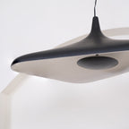Close view of the black shell and pale inner surface of this Clérachic disc pendant, with a soft glow along its lower edge.