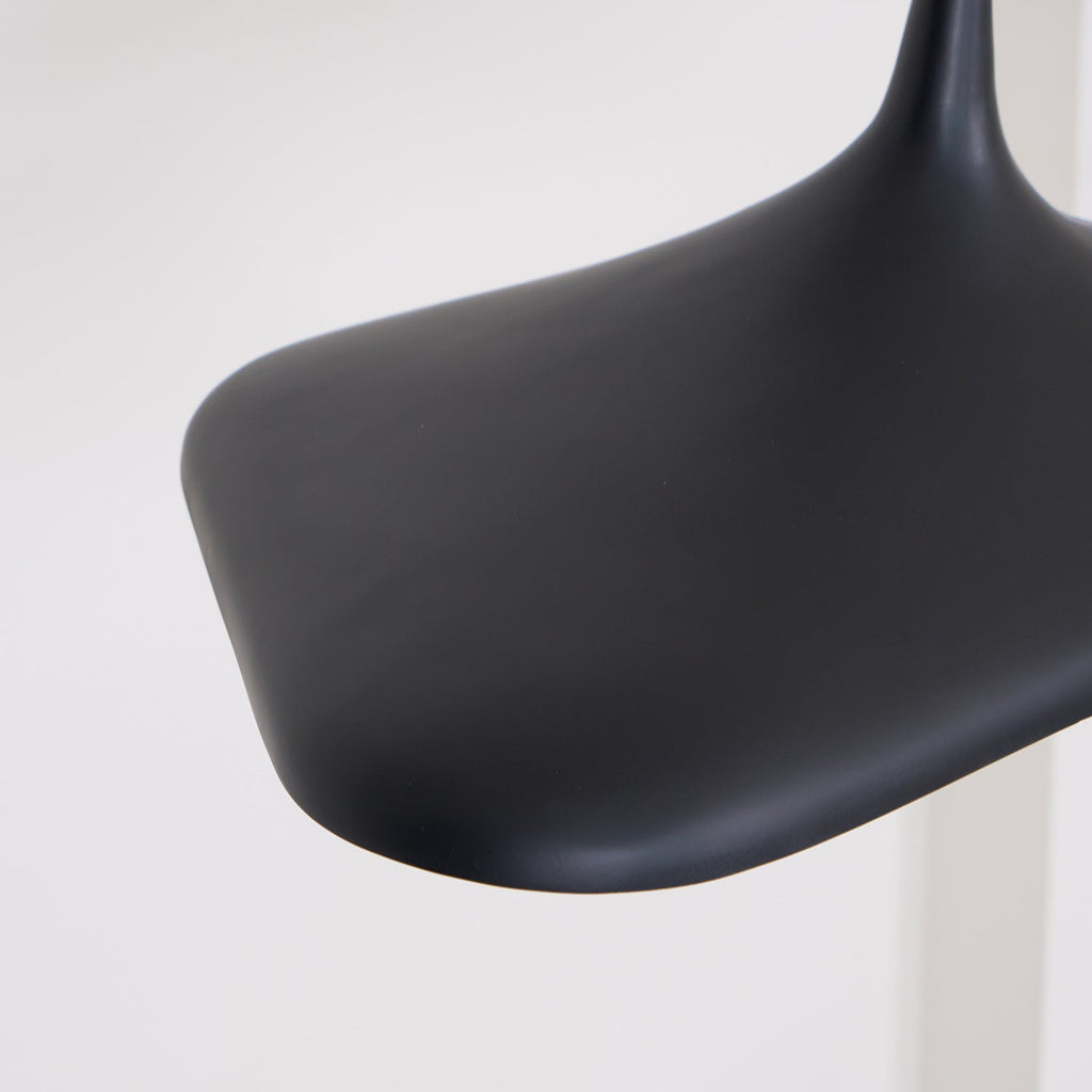 Close view of the smooth matt black edge of this Clérachic disc pendant, curving out from the slim neck, against a pale wall.