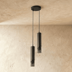 Clérachic two-head black cylinder pendant unlit, hanging at staggered heights from a round ceiling plate on thin cords.