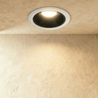 Clérachic large recessed downlight with a white trim and black cone, throwing a gentle warm wash over a plaster wall.
