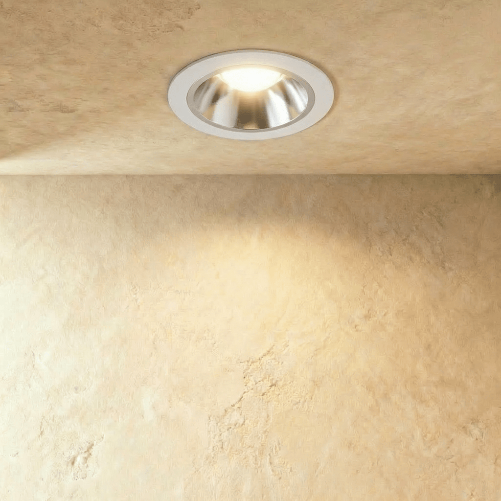 Clérachic recessed downlight with a white trim and brushed silver reflector cone, lit warm on a textured plaster ceiling.