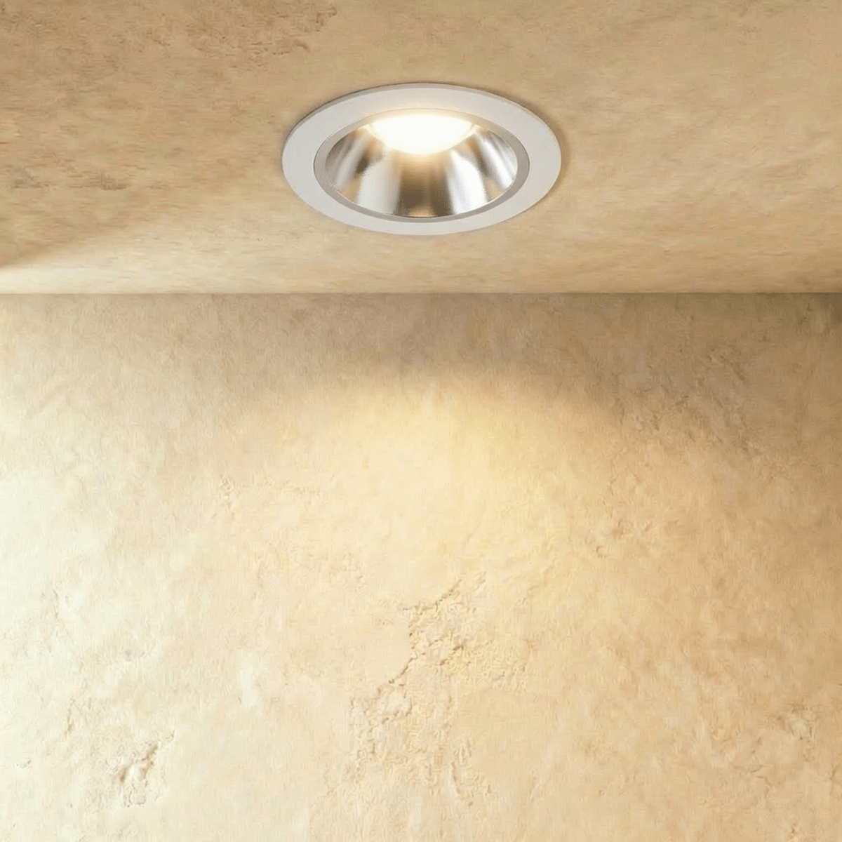 Clérachic recessed downlight with a white trim and brushed silver reflector cone, lit warm on a textured plaster ceiling.