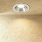 Clérachic medium recessed downlight with a white ring and satin silver cone, lighting a limewash wall with a warm glow.