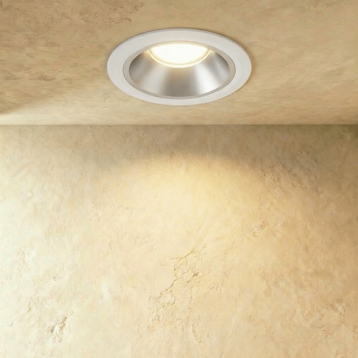 Clérachic medium recessed downlight with a white ring and satin silver cone, lighting a limewash wall with a warm glow.