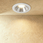 Clérachic large recessed downlight with a white trim and silver reflector, glowing warm above a textured sand-toned wall.