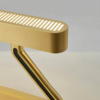 Close view of the Clérachic table lamp's brushed brass head with glowing slots, black inlay on the arm and rounded base.