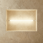 Clérachic linear wall lamp in white, the same glowing tube set across a plaster recess and filling it with warm light.