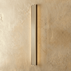 Clérachic slim black fluted LED bar wall light glowing warmly through three vertical light channels on limewash plaster.