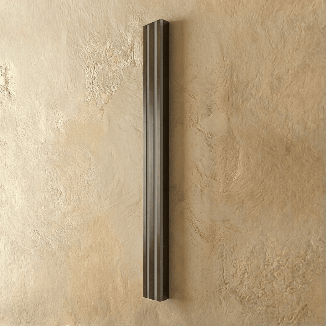 Clérachic slim black fluted bar wall light switched off, three ribbed vertical ridges on a textured plaster wall.