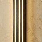 Close view of the Clérachic black fluted bar wall light, three glowing light strips between dark ribbed metal ridges.