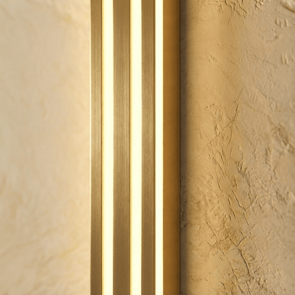 Close view of the Clérachic gold fluted bar wall light, brushed brass-tone ridges between three glowing light strips.