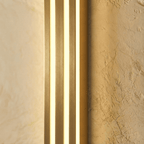 Close view of the Clérachic gold fluted bar wall light, brushed brass-tone ridges between three glowing light strips.