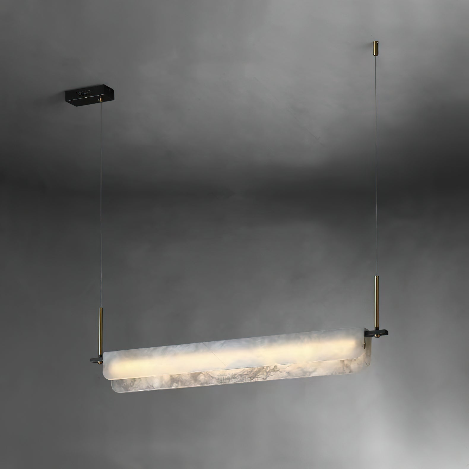Three-quarter view of the Clérachic Linear Alabaster LED Pendant Light on a dark grey wall, showing the twin-lipped stone profile lit from within.