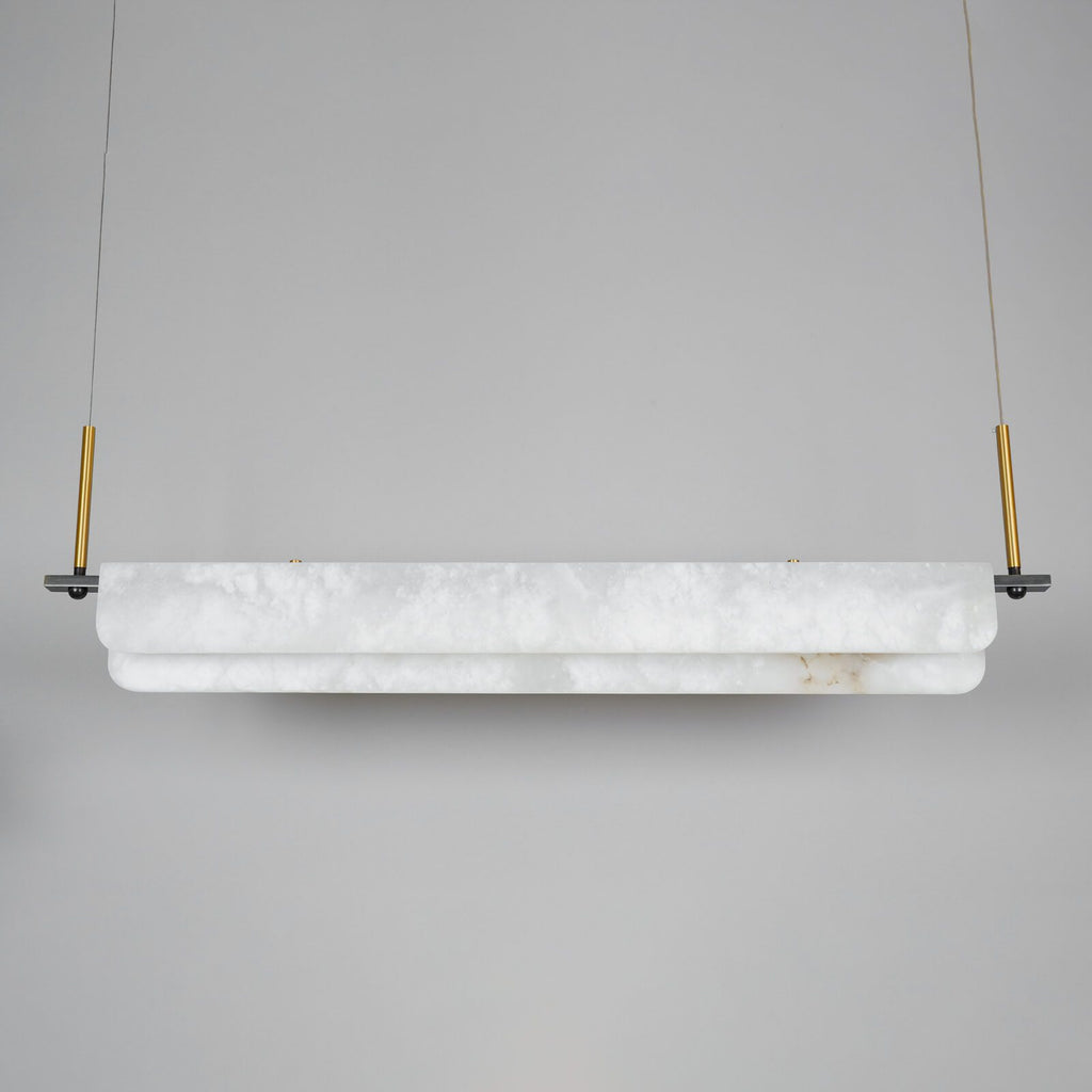 Clérachic Linear Alabaster LED Pendant Light switched off in the studio, the chalk-white alabaster and brushed brass droppers seen in daylight.