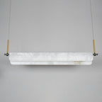 Clérachic Linear Alabaster LED Pendant Light switched off in the studio, the chalk-white alabaster and brushed brass droppers seen in daylight.