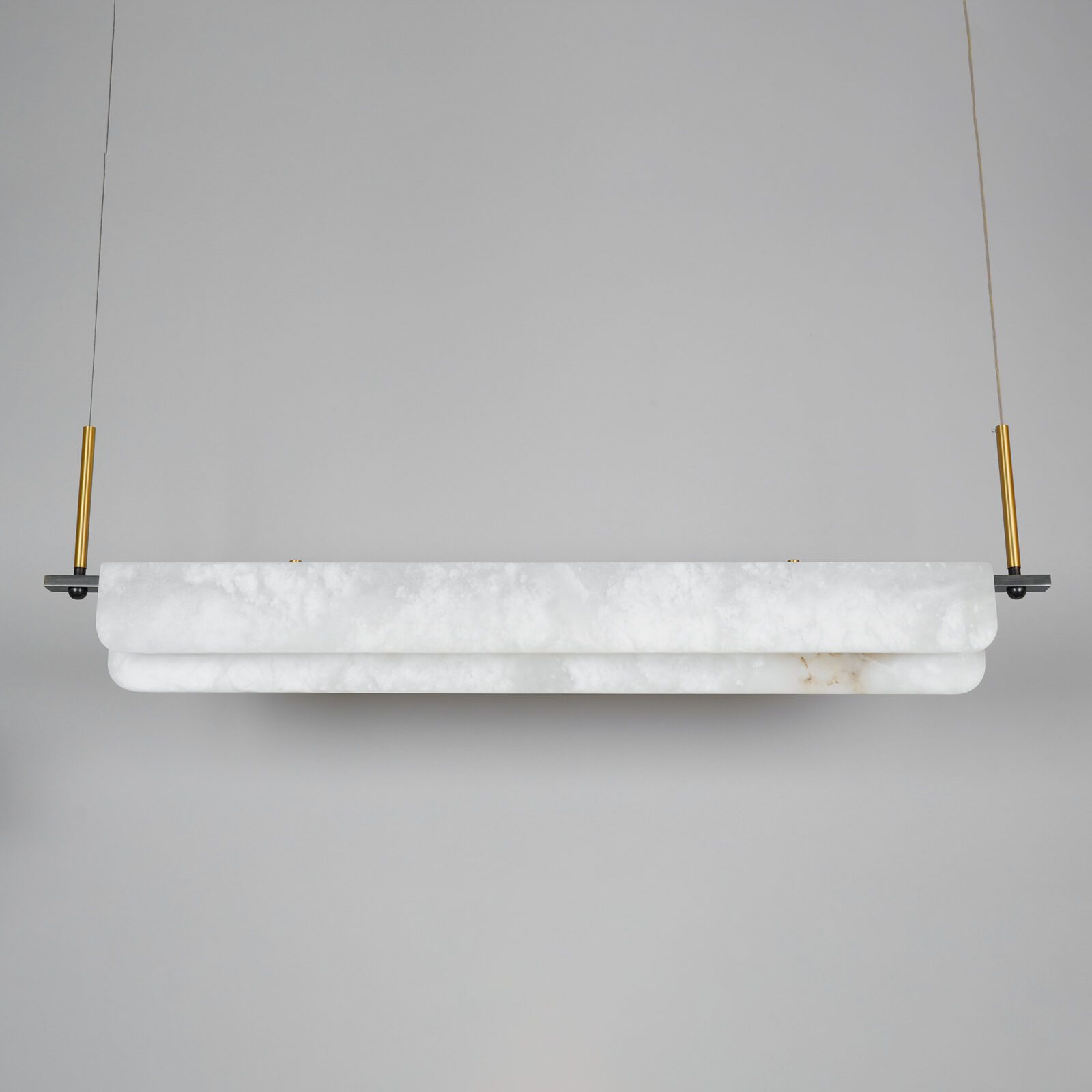 Clérachic Linear Alabaster LED Pendant Light switched off in the studio, the chalk-white alabaster and brushed brass droppers seen in daylight.