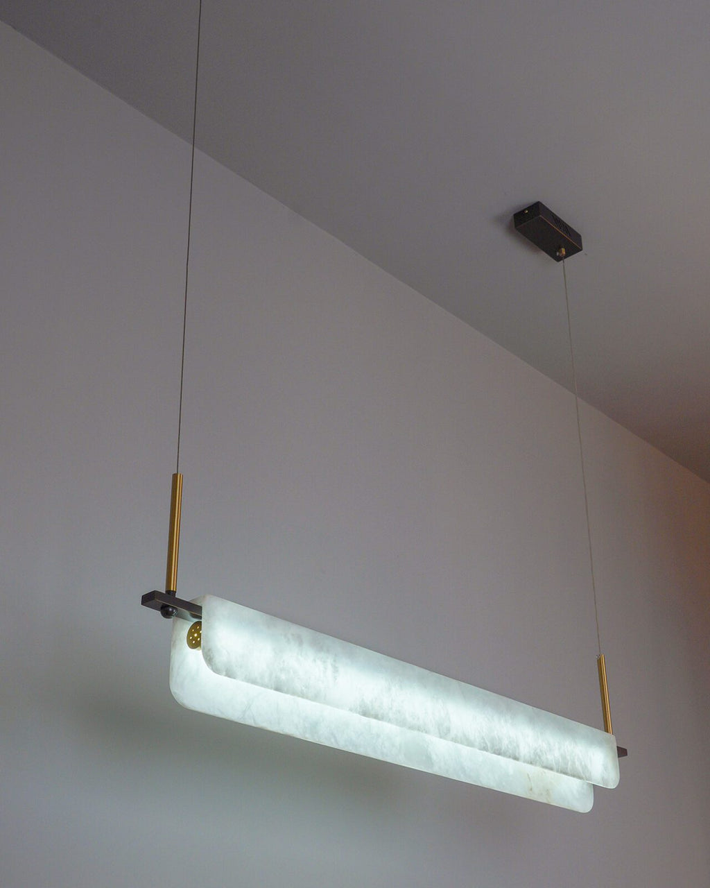 Clérachic Linear Alabaster LED Pendant Light lit in cool white, hung low from a white ceiling so the stone reads crisp over a working island.