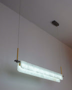 Clérachic Linear Alabaster LED Pendant Light lit in cool white, hung low from a white ceiling so the stone reads crisp over a working island.