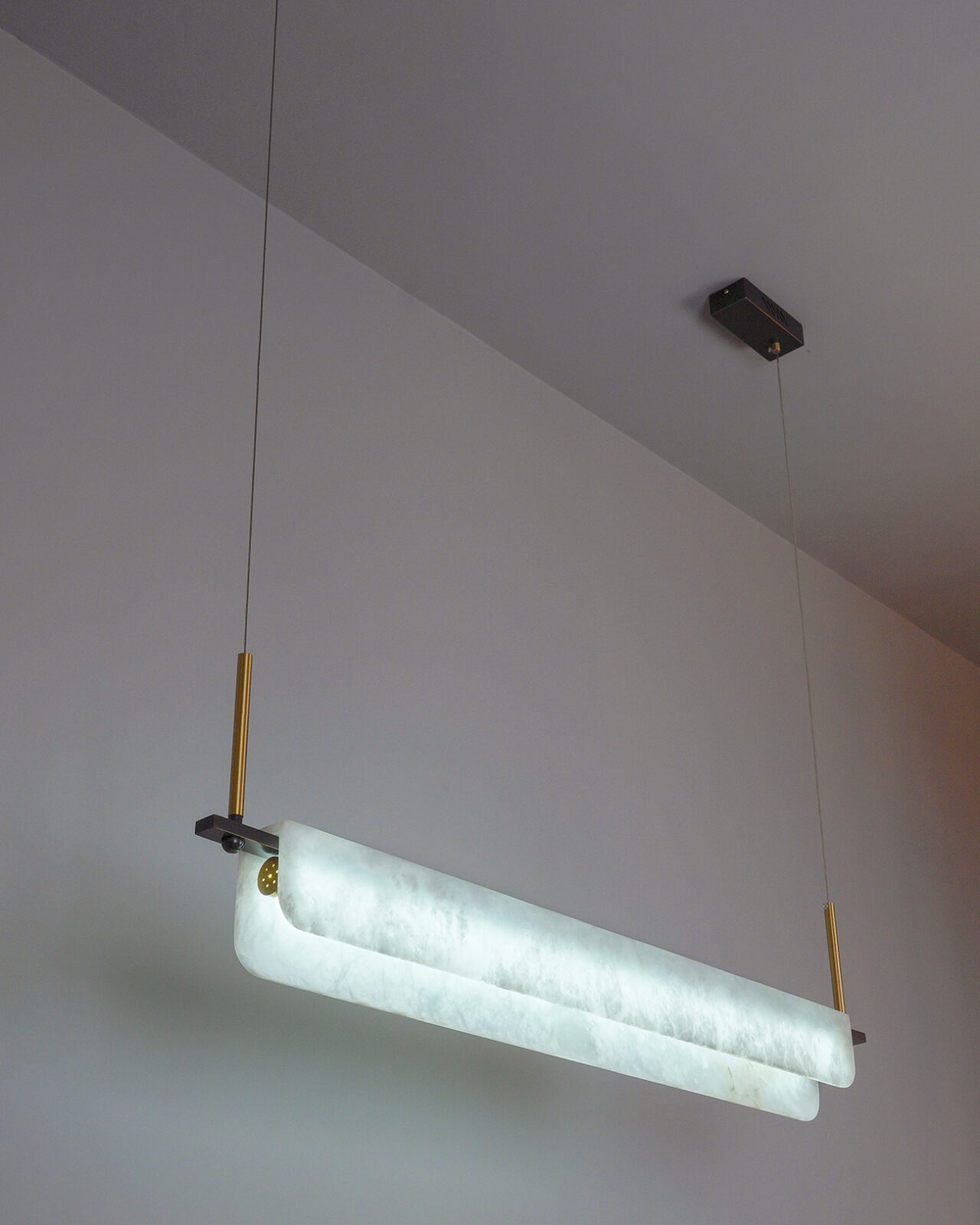 Clérachic Linear Alabaster LED Pendant Light lit in cool white, hung low from a white ceiling so the stone reads crisp over a working island.