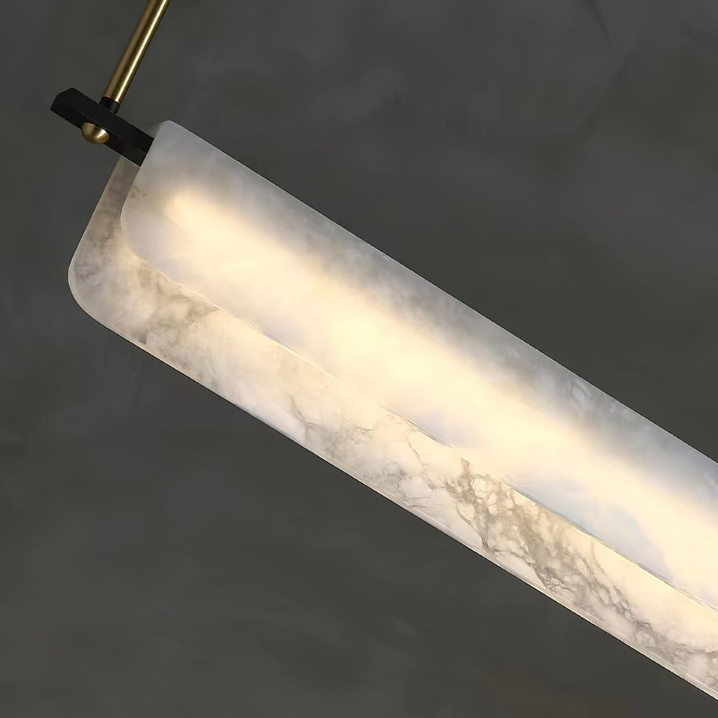 Close-up of the Clérachic Linear Alabaster LED Pendant Light, the grey-veined stone glowing at its rounded end beside a brass rod and black bracket.