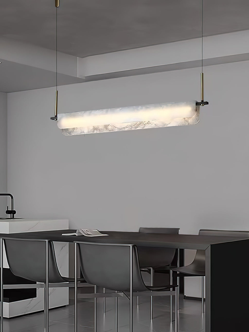 Clérachic Linear Alabaster LED Pendant Light over a long dark dining table beside a pale kitchen island, lighting the table evenly end to end.