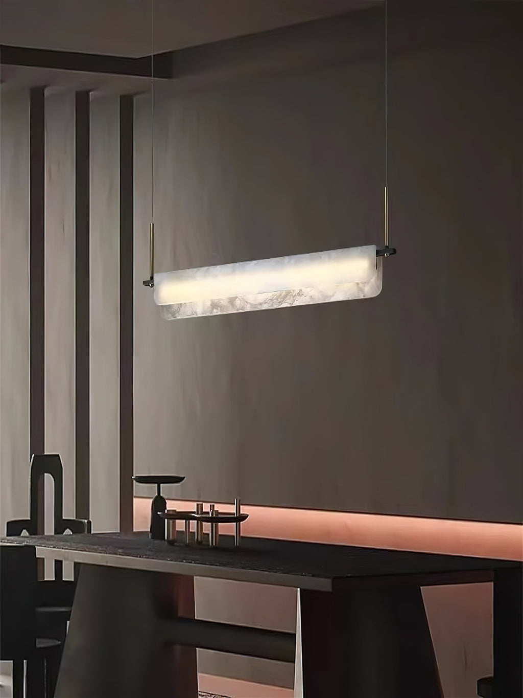 Clérachic Linear Alabaster LED Pendant Light glowing in a dim, dark-walled dining room, the stone the brightest thing above the table.