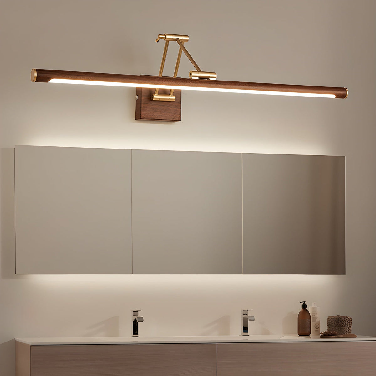 Lit above a long wall cabinet in a bathroom, this Clérachic linear wall light washes the mirror with warm light over a twin basin.
