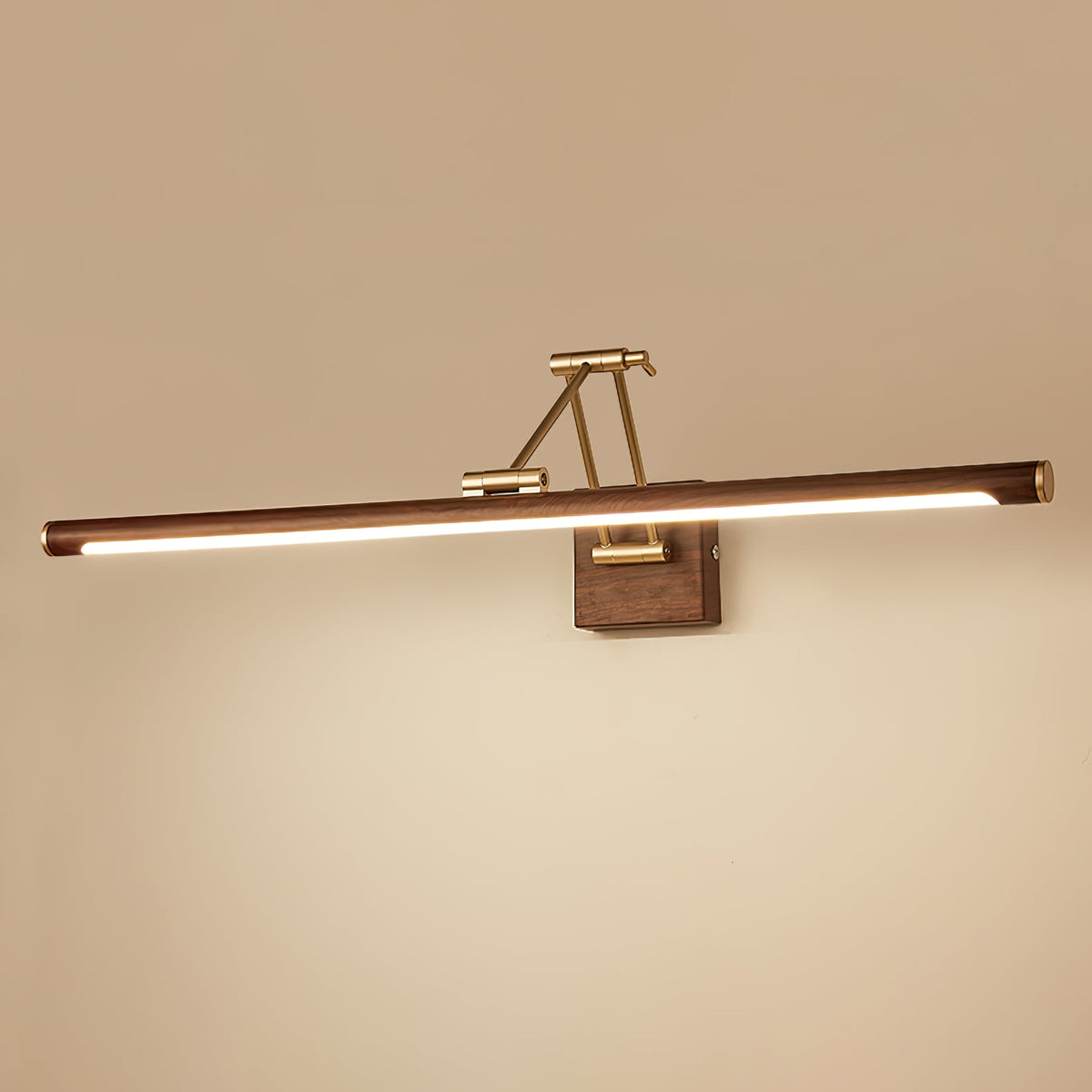 The walnut tube and brass arm of this Clérachic linear wall light glow against a warm beige wall, with a bright strip along the underside.