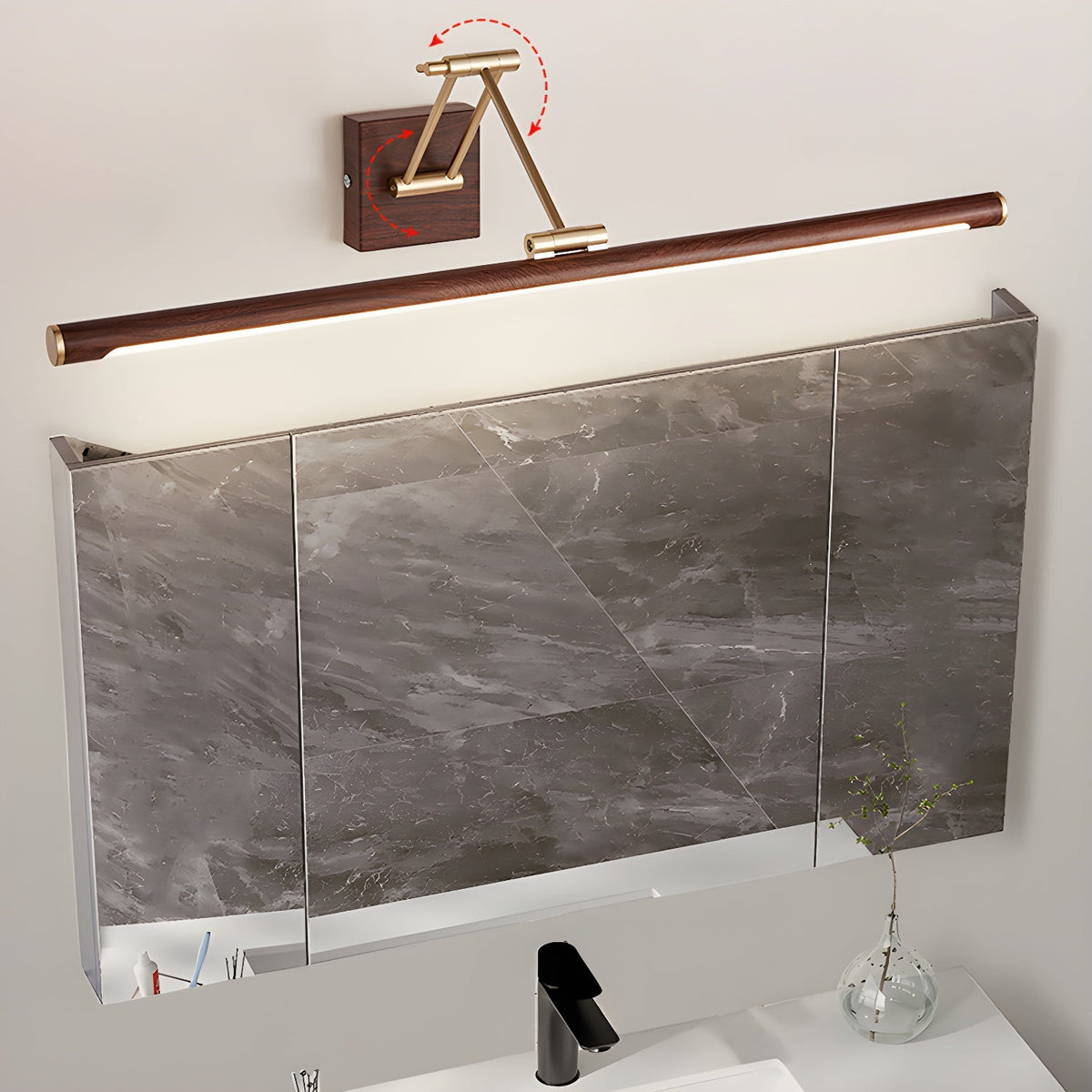This Clérachic linear wall light sits above a mirrored cabinet over a basin, with red arrows showing the folding arm swivelling.
