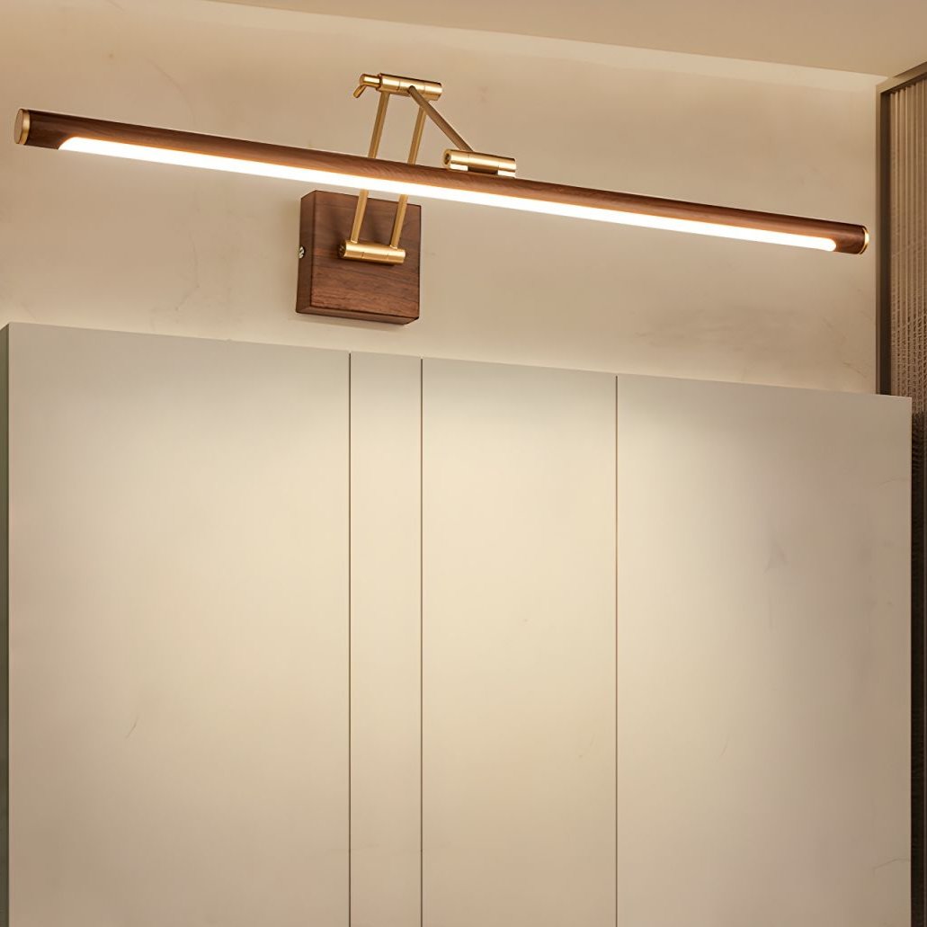 Lit Clérachic linear wall light above a tall cabinet with pale doors, glowing warm along the whole underside of the walnut tube.