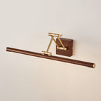 Unlit, angled view of this Clérachic linear wall light on a cream wall, with a brass arm folded over a walnut wall block.